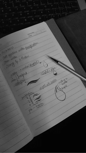 Open notebook with handwritten notes and diagrams on purification, alongside a silver pen. Background features a laptop keyboard. Black and white image.